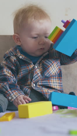 adorable small boy in shirt plays with color toy crawling on large soft bed in light children room closeup