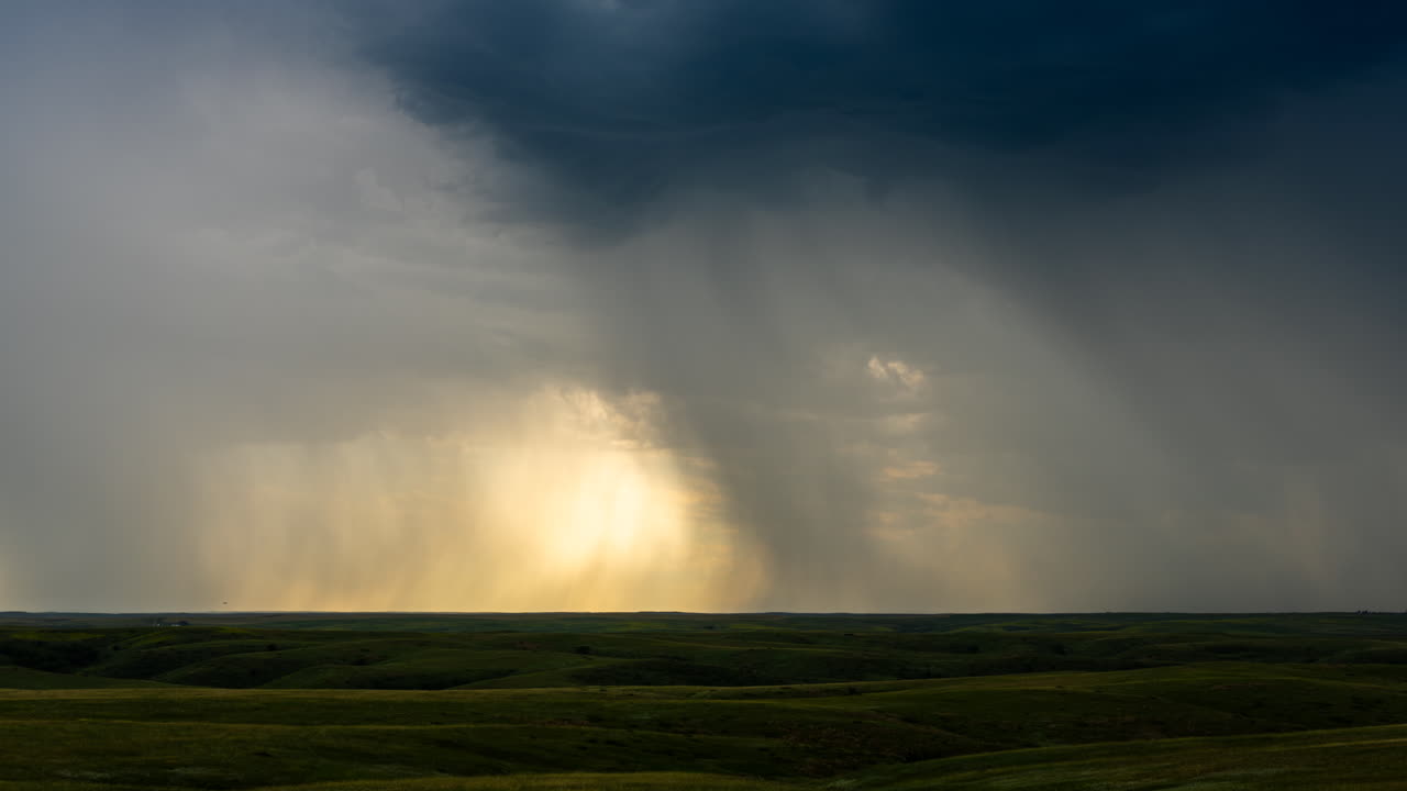 Beautiful green hills with bands of rain falling through a colorful sunset sky