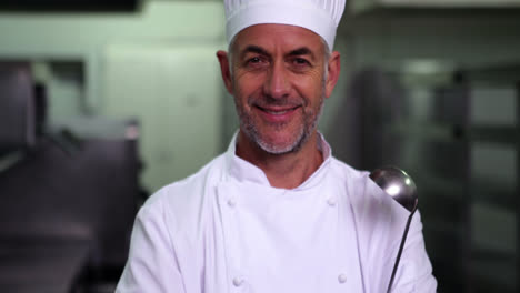 head chef holding a ladle smiling at camera