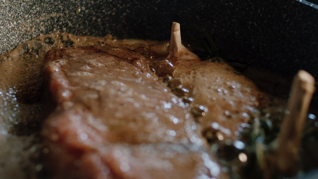 Garlic-Butter steak covered with  rosemary herbs in hot iron pan, rack focus