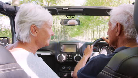 pasajero trasero pov de una pareja de ancianos conduciendo un coche con techo abierto