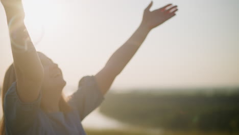 a close-up shot of a woman in a blue dress with her hands raised joyfully as she jumps under the bright sun, capturing the warmth and happiness of the moment with beautiful sun flares