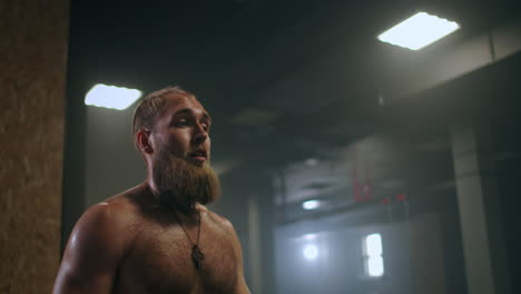 tired male athlete in the gym rests and prepares to perform an exercise. slow-motion sweaty athlete breathes heavily and concentrates on exercise