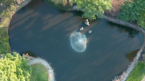 Rising-aerial-directly-above-water-fountain-spray-in-large-business-park