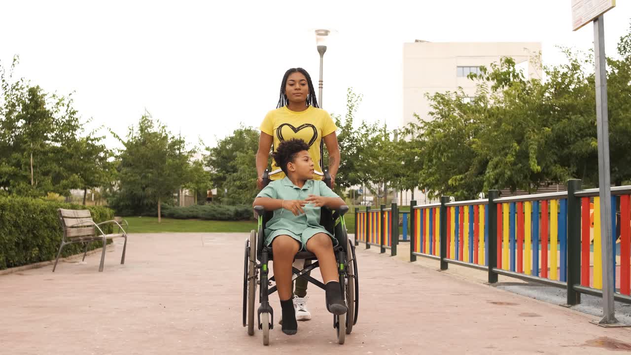 Woman pushing a child in a wheelchair in a park