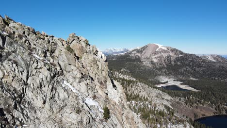 drone volando cerca de montañas nevadas hacia lagos alpinos y bosques en mammoth lakes california