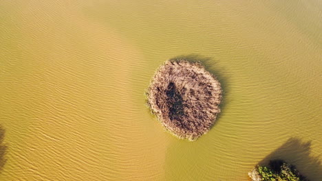 Aerial-tilt-up-shot-of-yellow-water-with-dried-islands-during-sunny-day-in-mud-badlands-of-Portugal