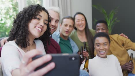 diverse group of happy male and female friends smiling and taking selfie in living room