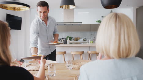 familia con padres ancianos y descendientes adultos comiendo juntos alrededor de la mesa en casa