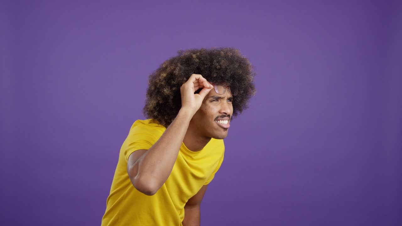 Man with afro hair adjusting glasses and looking with an intense expression