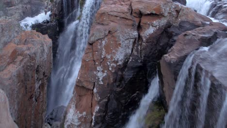 drone aerial tracking over rapidly falling fresh water on rough rocky terrain of the amber treur waterfalls in mpumalanga, south africa - reveal shot