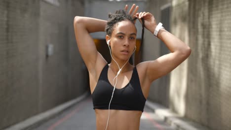 vista frontal de una joven mujer afroamericana atando su updo en la ciudad 4k