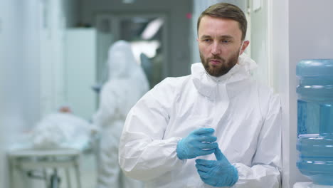 tired doctor in protective suit drinking water in hospital