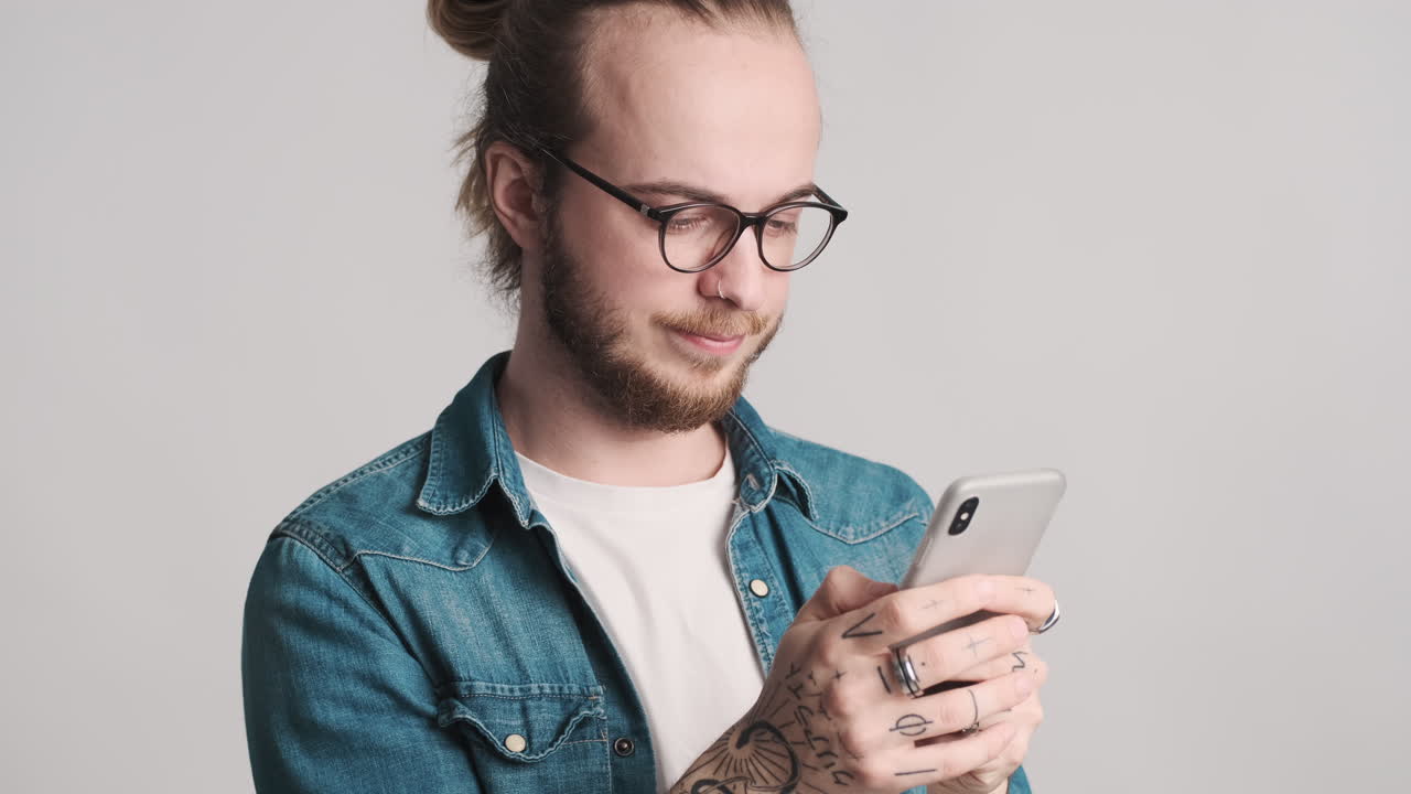 Caucasian young man texting on smartphone on camera.