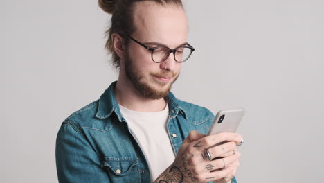 caucasian young man texting on smartphone on camera.