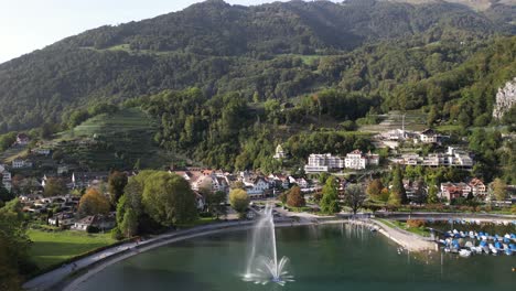 aerial zoom in shot of a lake with fountain with a town and lot of houses in the distance