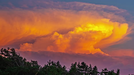 huge cumulonimbus cloud at sunset glows orange as it dynamically changes form - time lapse