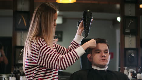 barber drying male hair in hairdressing salon. close up hairdresser blowing man hair with dryer in barbershop. male hairstylish doing hairdo in beauty studio