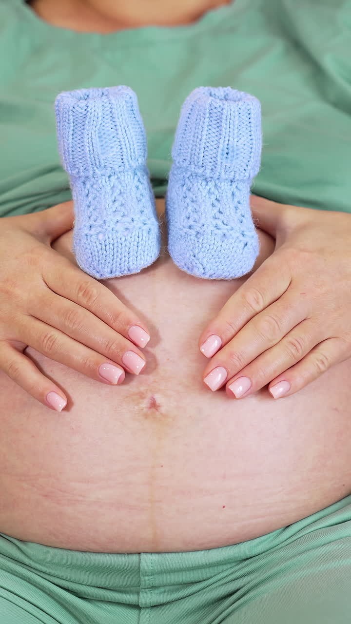 Donna incinta che si tocca la pancia. Primo piano di donna incinta seduta sul letto