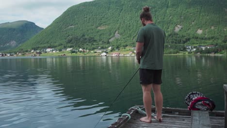 hombre caucásico pescando en el lago cerca de la aldea de medby en senja, noruega