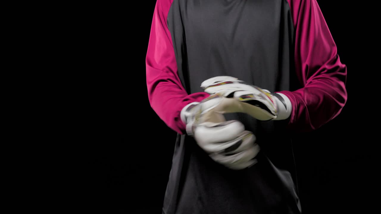 Video verticale: portiere maschio afroamericano che si sistema i guanti bianchi, preparandosi a giocare sul campo in erba sintetica.