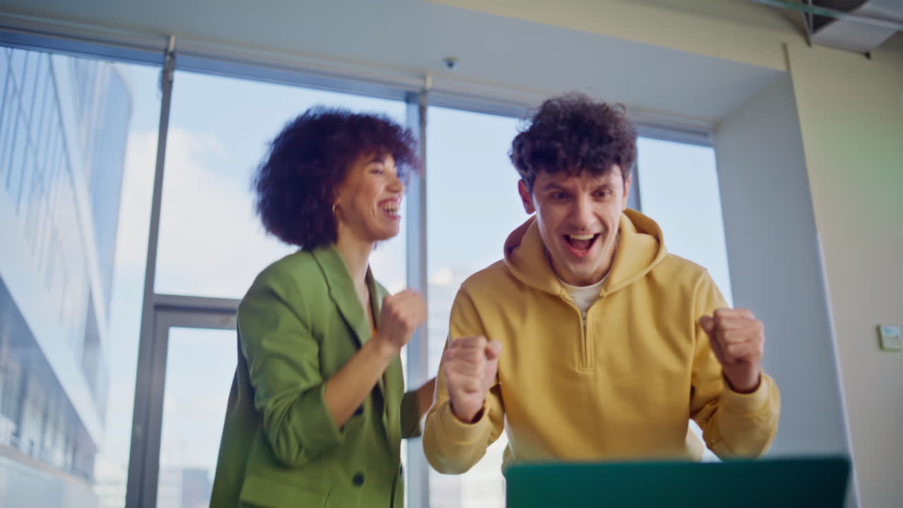 Emotional winners looking laptop rejoicing business success in office closeup