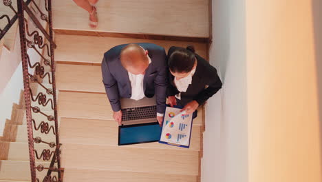 vista de arriba de los socios analizando los informes en la escalera