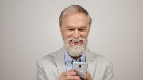 Hombre-Sonriente-Sosteniendo-El-Teléfono-Celular-Dentro.-Caballero-De-Edad-Mirando-El-Teléfono-En-El-Interior.