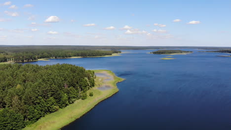 aéreo: vuelo lento sobre el lago azul hacia el horizonte lleno de bosques verdes