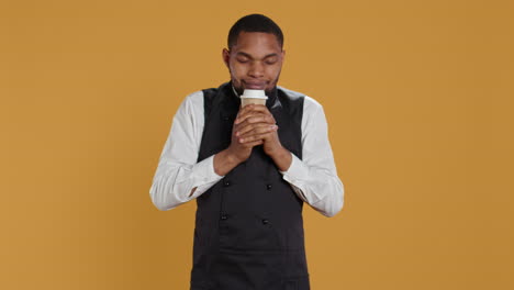 Cheerful-waiter-drinking-a-cup-of-coffee-and-relaxing-after-serving-clients