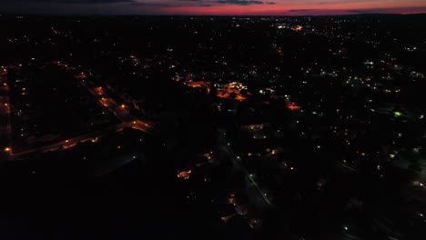 aerial approaching shot of american city at night with lighting streetlamps