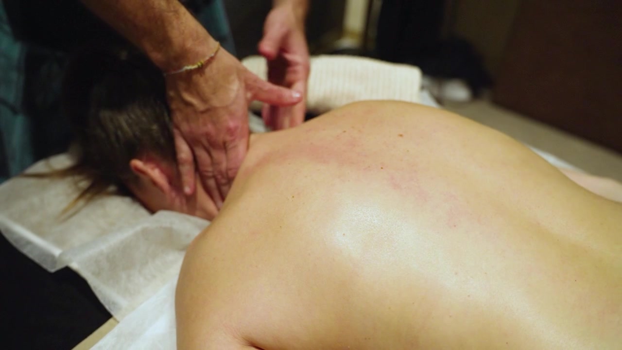 Terapeutisk nakke- og skuldermassage: Sidebillede af massørens hænder i aktion på spa
