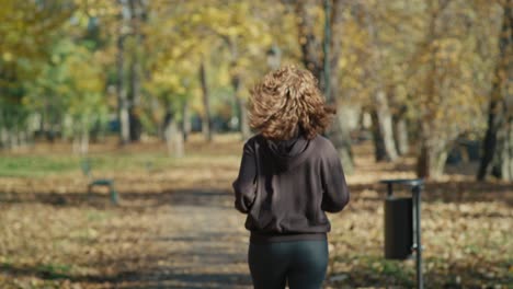 rear view of ginger woman running at the park in autumn