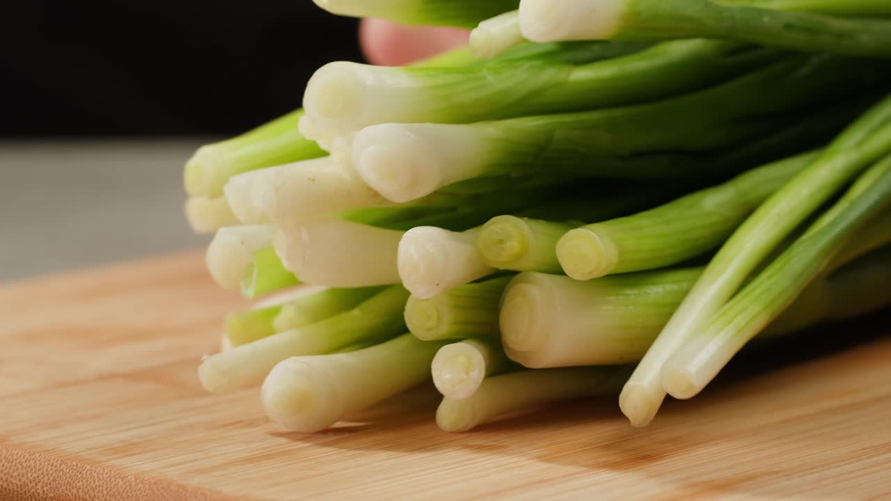 Cutting fresh green onions on a cutting board, close up chef cooking green vegan salad.