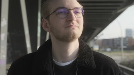 Young-European-Man-with-Glasses-and-Beard-Walking-on-Sidewalk-in-Hamburg,-Germany