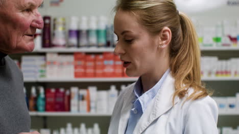 mujer joven hablando con un hombre mayor en la farmacia.