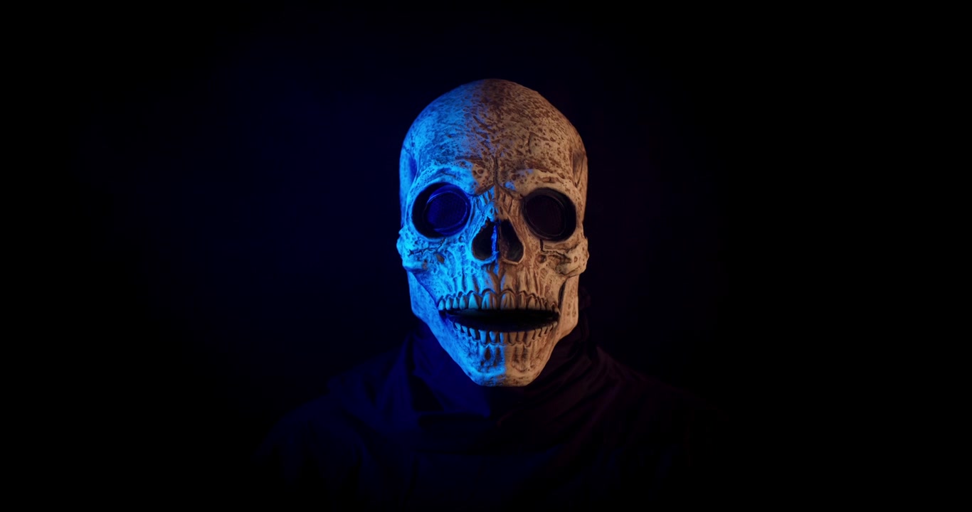 Persona che indossa una maschera a teschio dietro un ciak cinematografico