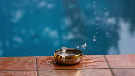 slow motion shot of an object dropping into a bowl and water splashes out