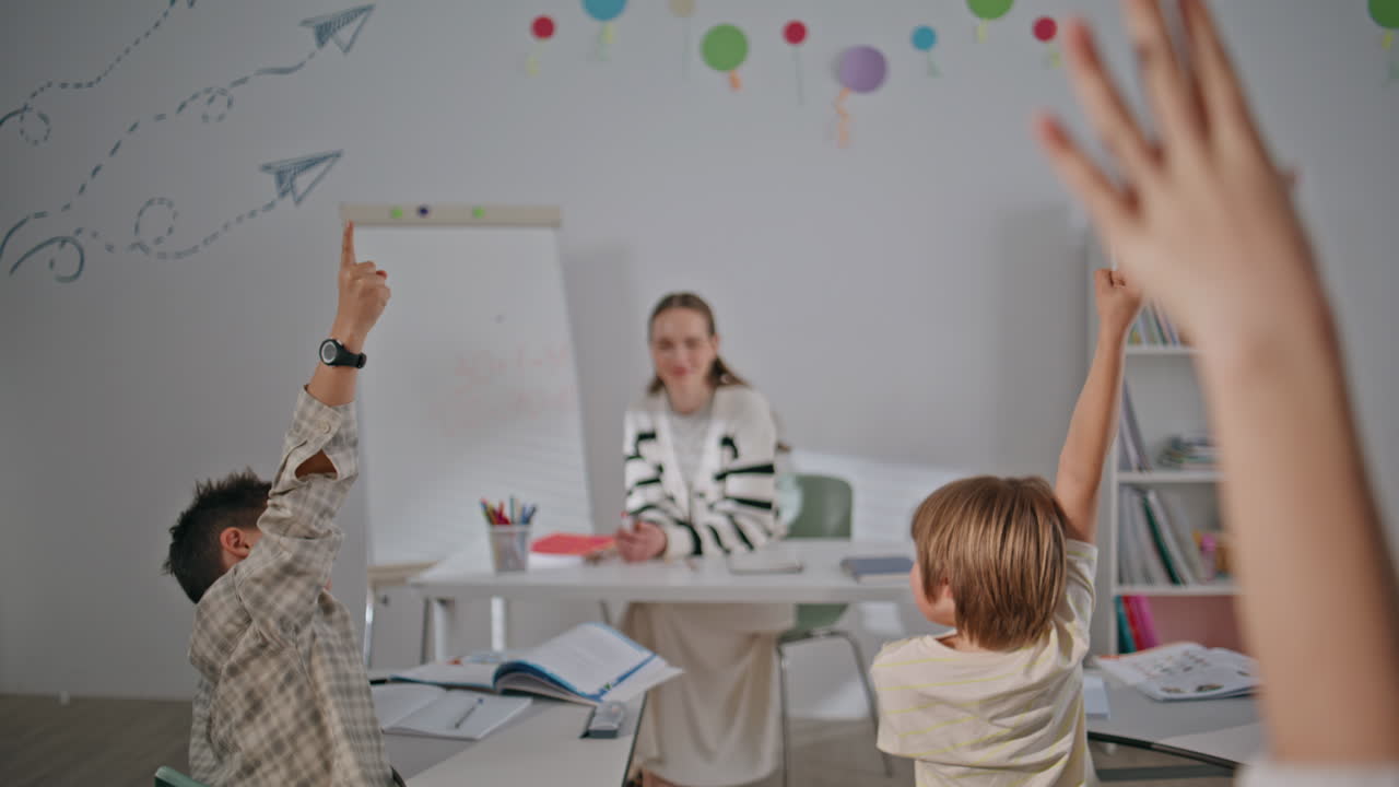 Raising hands kids answering lesson sitting desks in school class back view