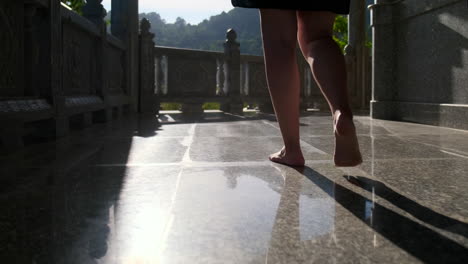 mujer caminando descalza por un piso de piedra en un templo