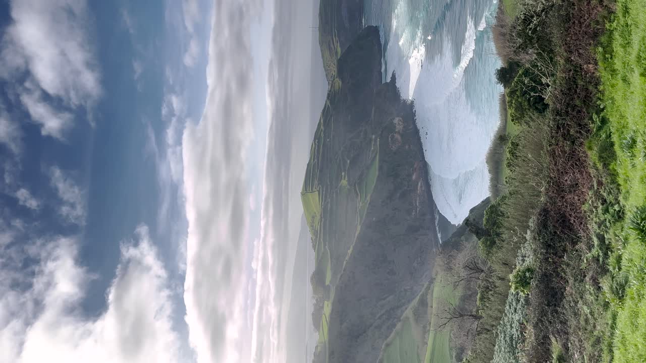 video vertical de las ondas rítmicas del océano que caen en cascada en las orillas de la riviera portuguesa en las azores, portugal, encapsulando el sereno encanto costero y el impresionante paisaje natural