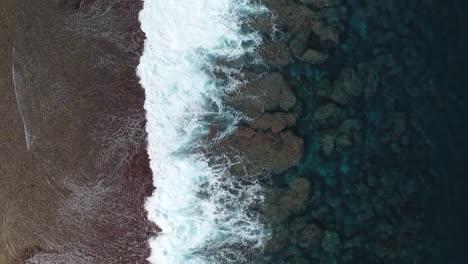 Bird's-eye-view-of-ocean-waves-crashing-against-shore-in-Loyalty-Islands,-New-Caledonia