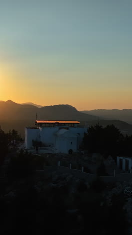 vertical drone shot orbiting the tsambika monastery, sunset in rhodes, greece