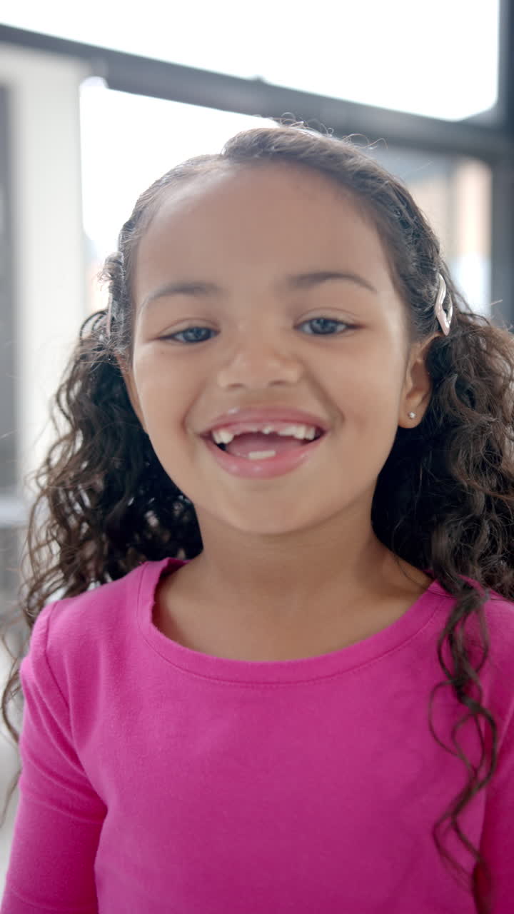 Vertical video: In school, young biracial girl smiling at camera