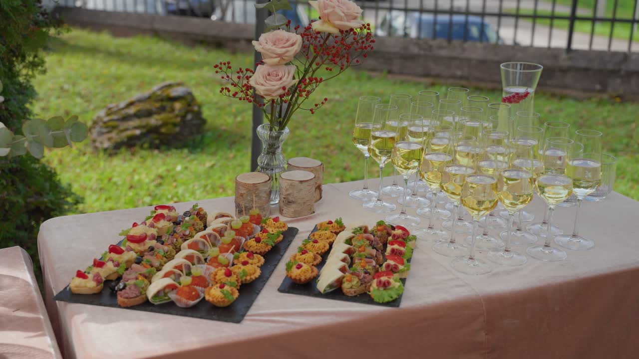Un tavolo da buffet esterno splendidamente allestito con un assortimento di antipasti colorati e calici scintillanti. L'illuminazione naturale esalta l'atmosfera festosa in un ambiente da giardino