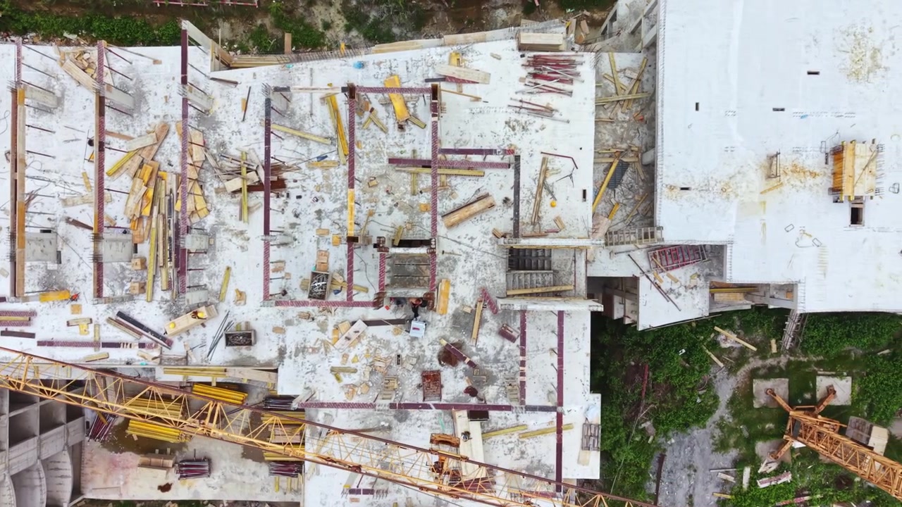 Área de construcción deteriorada con maquinaria desgastada y vegetación trepadora. La infraestructura en descomposición en este sitio vacío presenta equipo corroído y vida vegetal invasora.