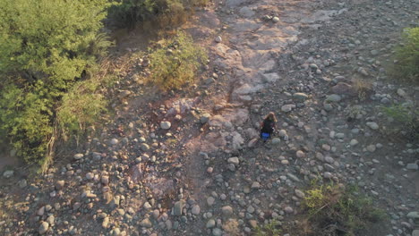 aerial drone desert hike with woman backpacker climbing terrain in hot desert in the early morning