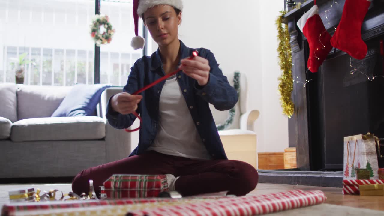 mujer con sombrero de santa envolviendo regalos de navidad en casa