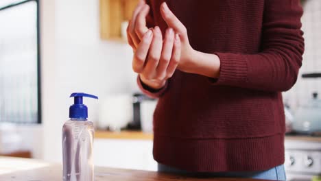 Mid-section-of-woman-sanitizing-her-hands-at-home