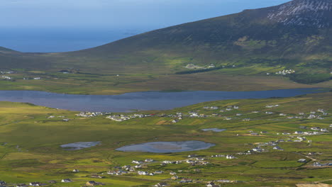 lapso de tiempo del pueblo costero y el paisaje de la ladera del lago con nubes que proyectan sombras a la luz del día vistas desde las alturas de minaugn en la isla de achill en el condado de mayo en irlanda